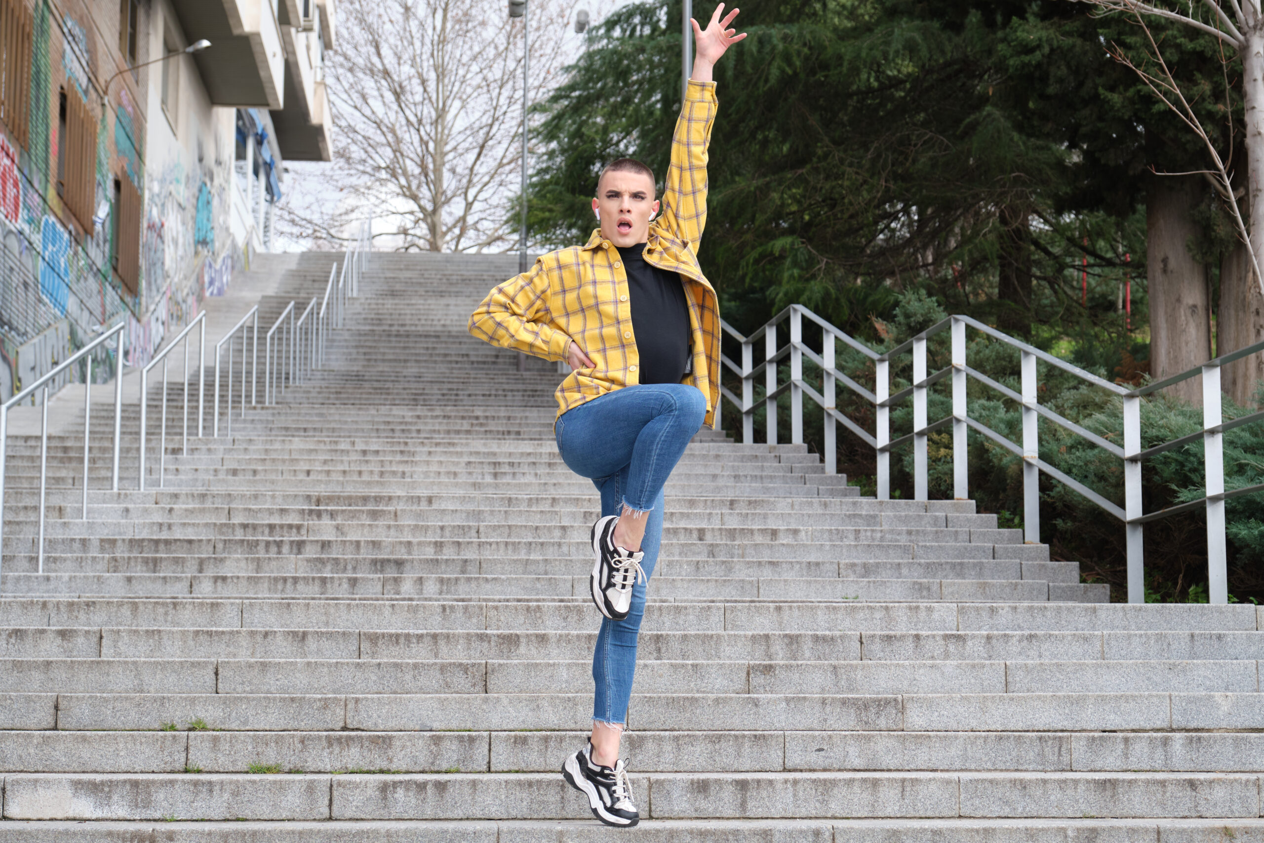 Handsome young man wearing make up, dancing on stairs. Non binary androgynous guy.